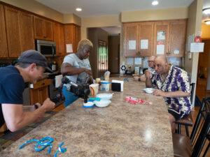 People standing and sitting around a kitchen island having ice cream.