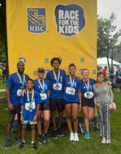 Group of people with running gear on posing in front of a race banner