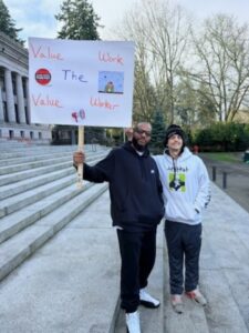 Two people on the Washington State Capitol steps holding a sign.