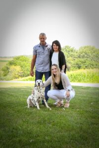 Three people and a dog posing outside for photo.
