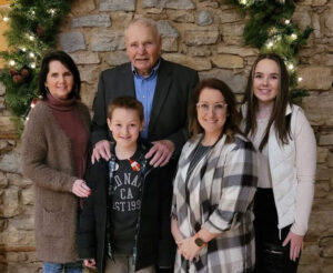 Family photo, five people standing in front of a stone wall inside a church.