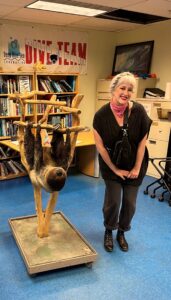 Hayley posing for photo next to a sloth exhibit.
