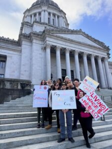 People with signs standing on the capitol steps.