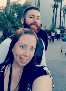 Jennifer McAlpine with her husband outside and palm trees in the background.