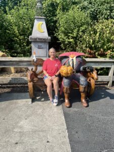 Sheri Butler sitting on a bench next to a sitting statue of the Headless Horseman.