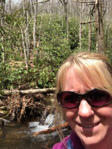 Sheri Butler in foreground with trees and river in the background.