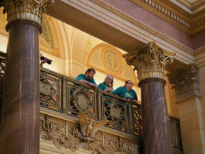 Three Dungarvin staff members looking over the balcony of the third story of the Minnesota State Capitol Rotunda.