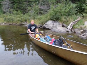 Greg Degel sitting in a canoe on the water.