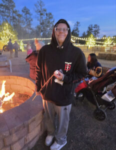 Luca standing outside by a firepit smiling.