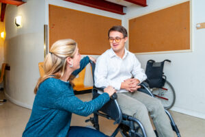 Woman DSP talking to a young man in a wheelchair.