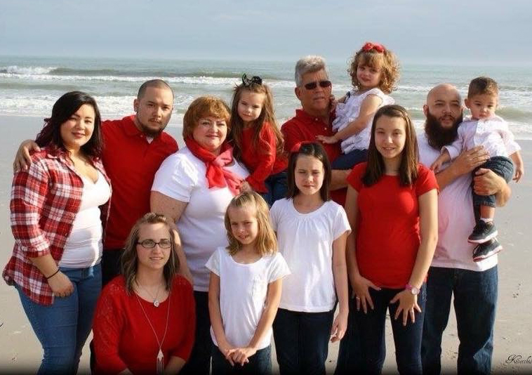 Large group family photo on the beach with ocean in the background.