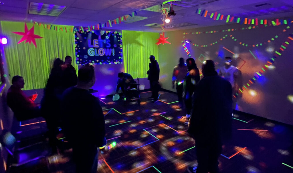 Darkened room with black lights and neon colored decorations.