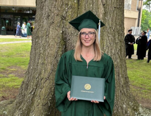Suzanne Craig in graduation cap and gown holding her bachelor's degree.