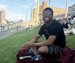 Quan sitting on the grass smiling.