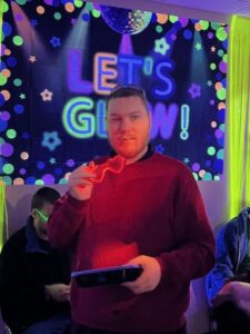 Sean, an individual served, in the Glow Party room, which is dark with colorful neon lights.