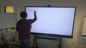 Person writing on a digital whiteboard.