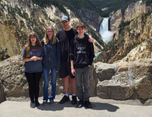 Suzanne Craig with her family standing in front of a waterfall in the mountains.