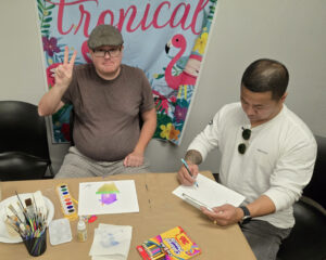 Individual served sitting at a table working on a watercolor painting.