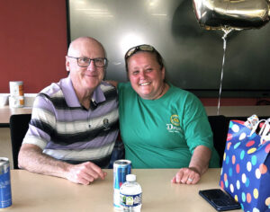 Bea Morehouse sitting at a table with Tim Madden, both smiling and posing for photo.