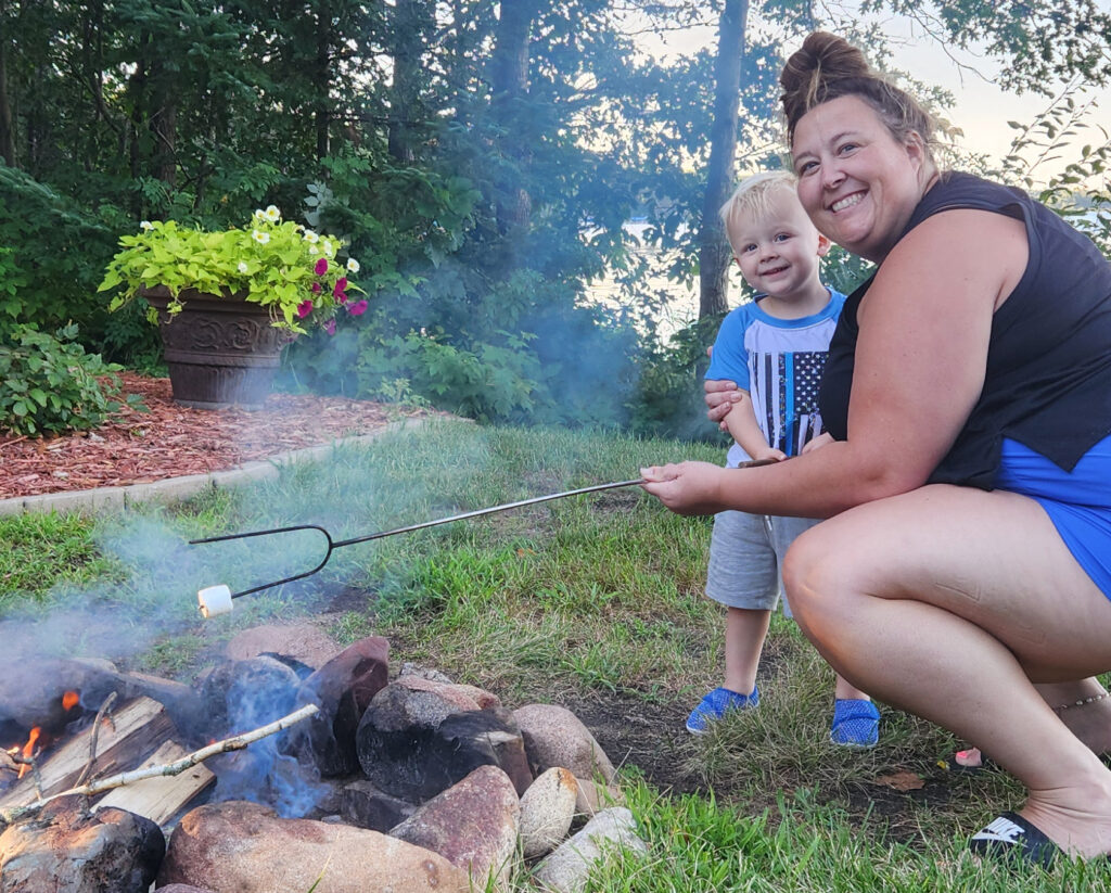 Emilee Sames outside with her son by a campfire.
