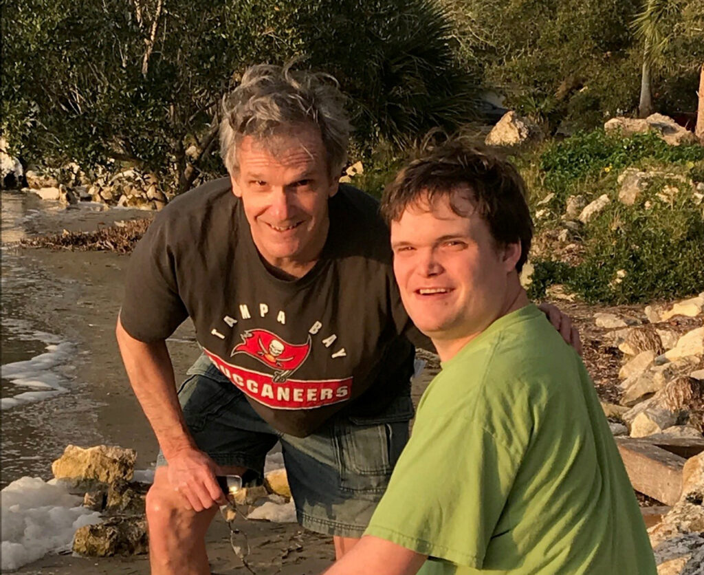 Jeff Rawlins with his son Chris sitting on a rocky river shore.