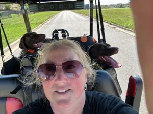 Lee-Ellen Bailey in a golf cart with her two dogs sitting behind her.