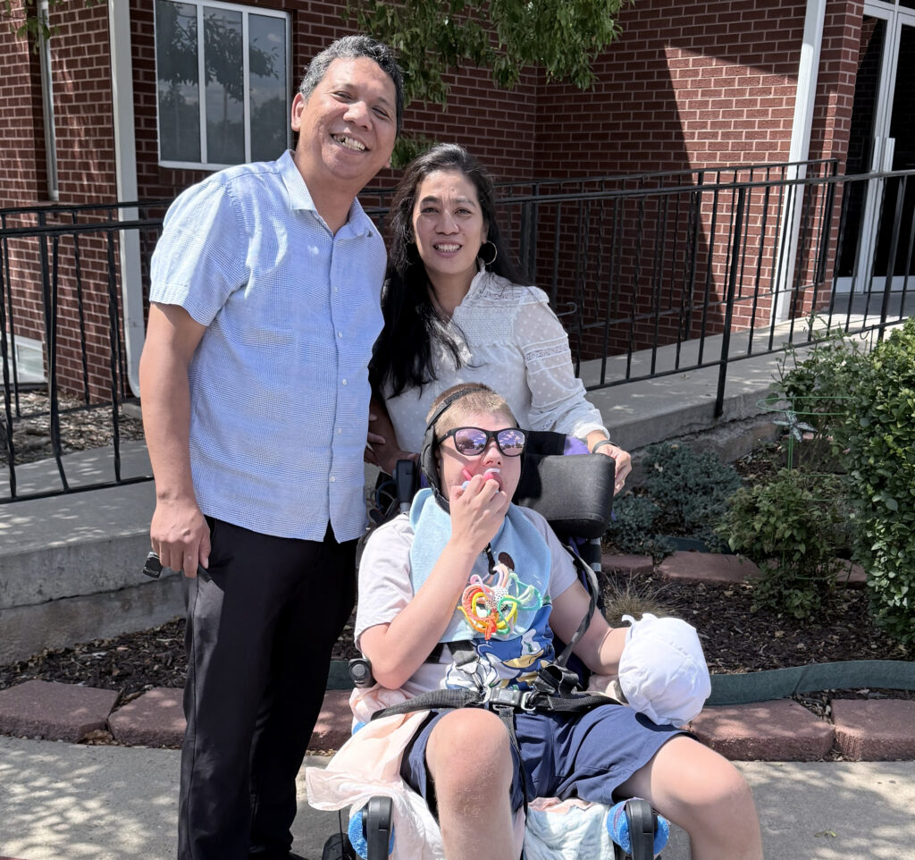 Dearmi and Anto standing behind Jonathan in hi wheelchair.