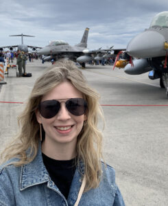 Sarah Cave standing outside with fighter jets in the background.