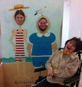 Carissa laughing in front of a photo stand-in cutout board with Eloise and another person in it.