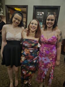 Taylor Zahn with her mom and sister, all wearing dresses and smiling for the camera.
