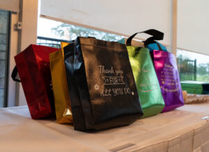 Several gift bags of different colors sitting on a table.