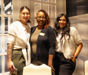 Three women smiling and standing together.