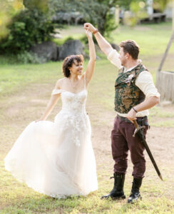 Taylor Zahn in a wedding dress, outside, in a dancing pose with her husband Joelson.