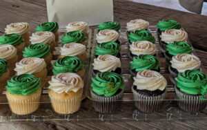 Green- and white-frosted cupcakes laid out on a table.